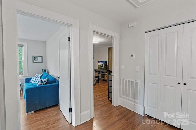 hallway featuring visible vents, wood finished floors, and baseboards