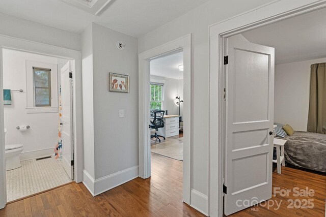 corridor with visible vents, wood finished floors, and baseboards