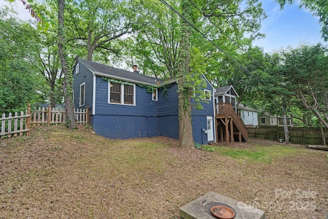 exterior space featuring a wooden deck, stairway, a fenced backyard, and a chimney