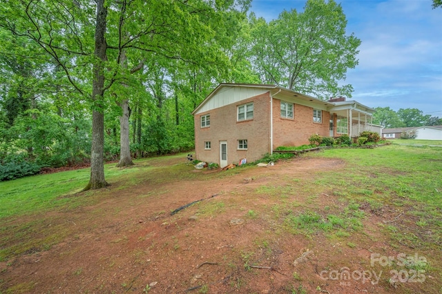 view of side of property featuring a lawn, brick siding, and a chimney