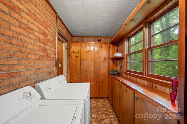 laundry room with an ornate ceiling, wood walls, brick wall, and washer and dryer