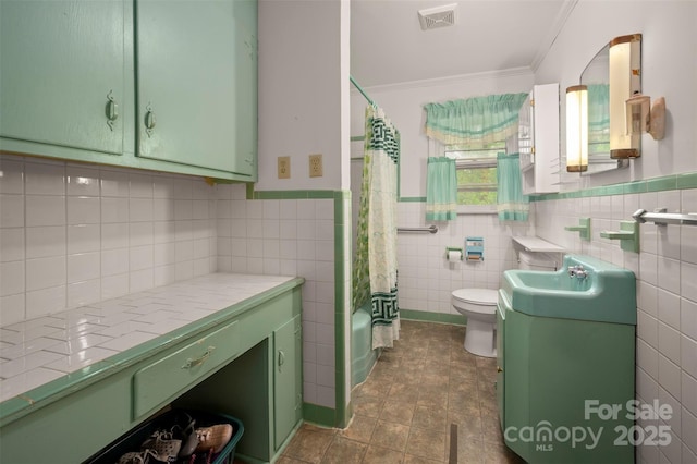 full bathroom featuring visible vents, crown molding, tile walls, vanity, and toilet