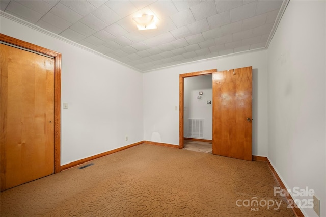 unfurnished bedroom with carpet floors, ornamental molding, baseboards, and visible vents