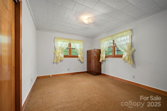 carpeted empty room featuring baseboards and ornamental molding