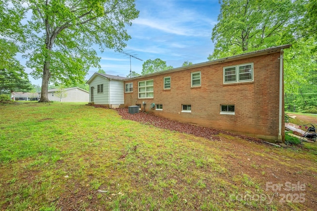 back of property featuring a lawn, brick siding, and central AC