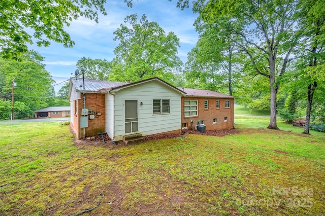 back of property with a lawn, metal roof, and cooling unit