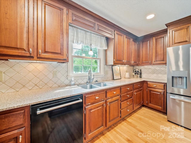 kitchen with brown cabinets, light wood-style flooring, a sink, dishwasher, and stainless steel fridge with ice dispenser