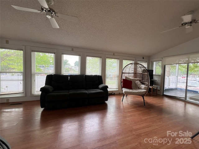 living room with a textured ceiling, ceiling fan, wood finished floors, and lofted ceiling