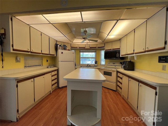kitchen featuring a sink, white appliances, light countertops, light wood-style flooring, and white cabinetry