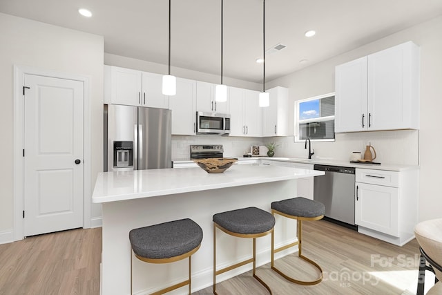 kitchen featuring a breakfast bar area, tasteful backsplash, stainless steel appliances, and light wood finished floors
