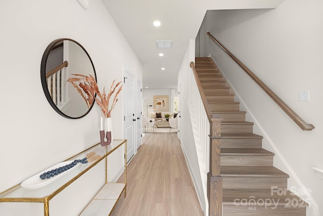 stairway featuring wood finished floors, recessed lighting, and visible vents