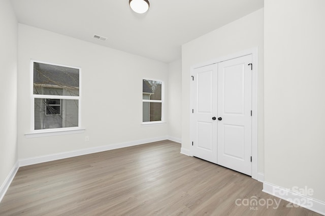 unfurnished bedroom featuring wood finished floors, visible vents, and baseboards