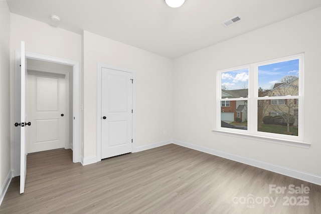 unfurnished bedroom with visible vents, baseboards, and light wood-style floors