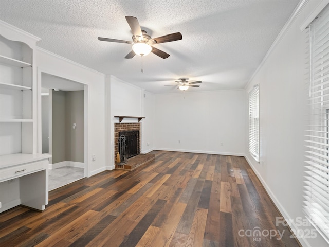 unfurnished living room featuring ceiling fan, ornamental molding, dark wood-type flooring, a textured ceiling, and a fireplace