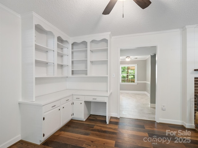 unfurnished office with a ceiling fan, dark wood-style floors, a textured ceiling, crown molding, and baseboards