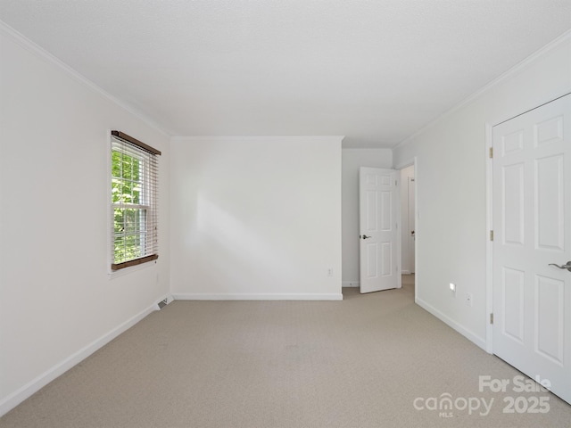 unfurnished bedroom with ornamental molding, light carpet, and baseboards
