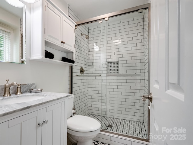 bathroom featuring a stall shower, toilet, and vanity