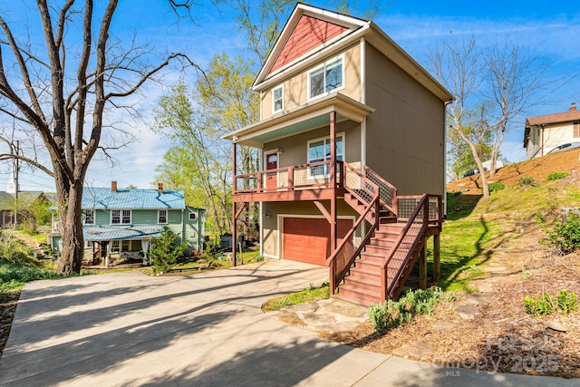 view of front of property featuring a garage, covered porch, stucco siding, concrete driveway, and stairway