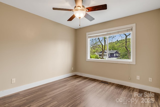 spare room featuring baseboards, a ceiling fan, wood finished floors, and visible vents