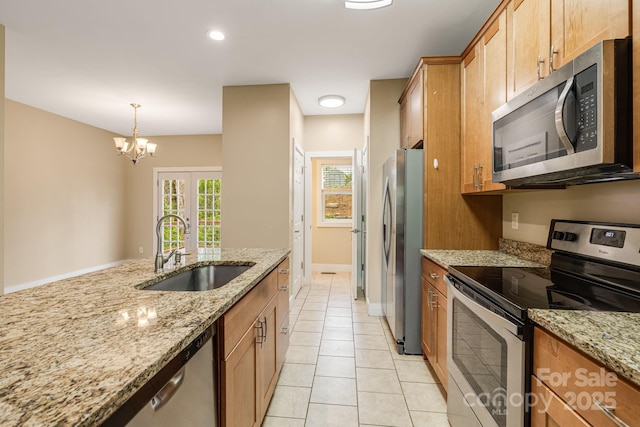 kitchen featuring pendant lighting, light stone countertops, a sink, stainless steel appliances, and light tile patterned flooring
