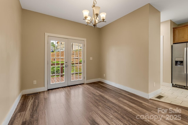 unfurnished dining area with light wood-type flooring, a notable chandelier, visible vents, and french doors