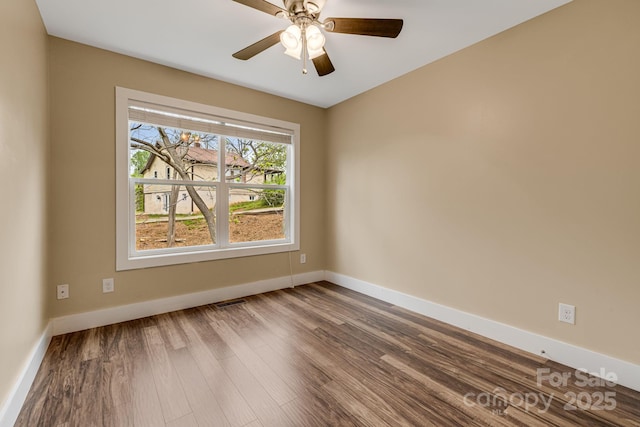 unfurnished room with baseboards, visible vents, a ceiling fan, and dark wood-type flooring