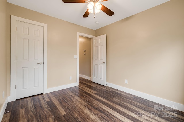unfurnished bedroom featuring baseboards, ceiling fan, and dark wood-type flooring