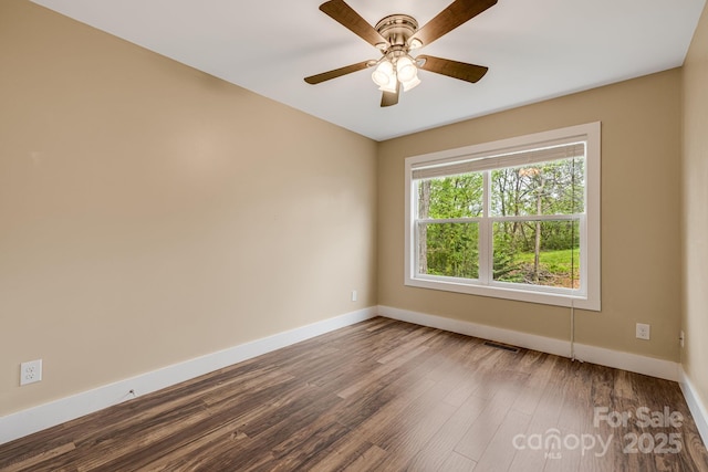 spare room featuring baseboards, a ceiling fan, dark wood finished floors, and visible vents