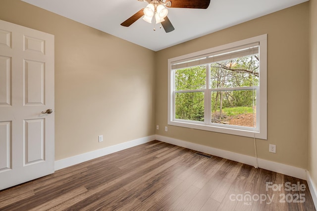 spare room featuring baseboards, ceiling fan, wood finished floors, and visible vents