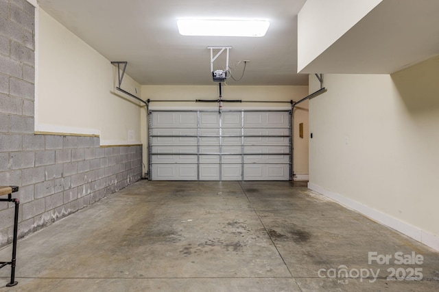 garage with a garage door opener and concrete block wall
