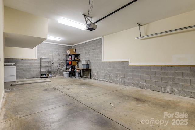garage featuring washer / dryer, concrete block wall, and a garage door opener