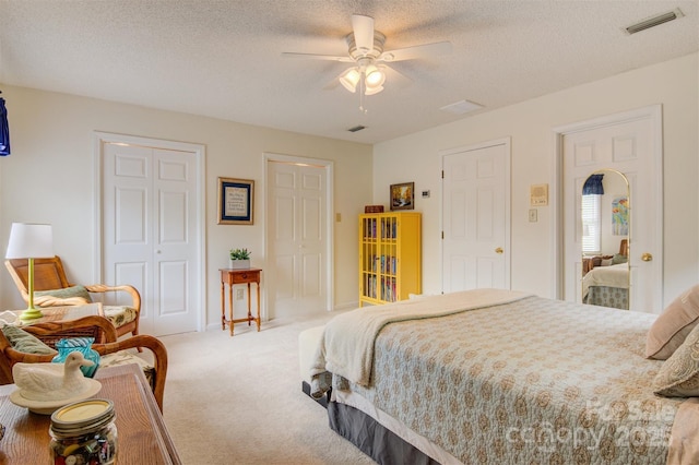 bedroom featuring a textured ceiling, carpet flooring, a ceiling fan, and visible vents