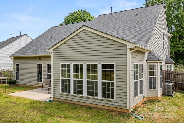 back of property featuring a shingled roof, a patio area, a yard, central AC, and fence