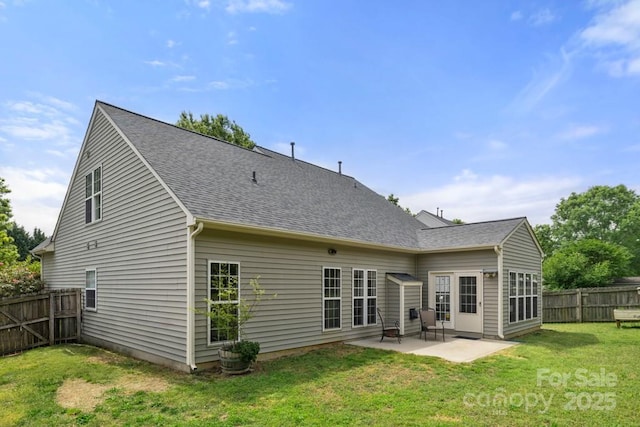 back of property featuring fence, roof with shingles, a patio area, and a yard