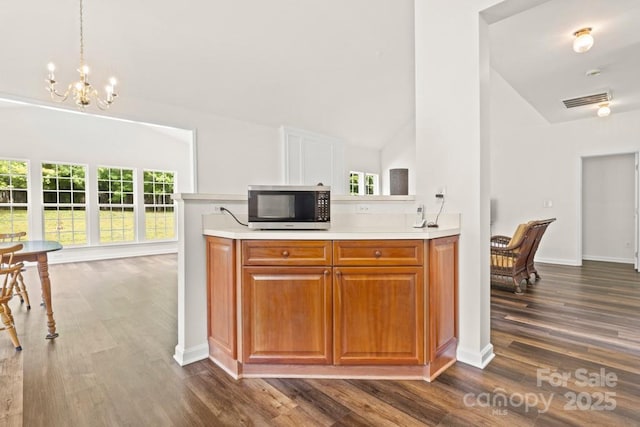 kitchen with stainless steel microwave, a chandelier, light countertops, dark wood-style flooring, and a wealth of natural light