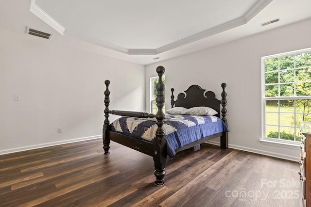 bedroom with crown molding, multiple windows, wood finished floors, and a tray ceiling