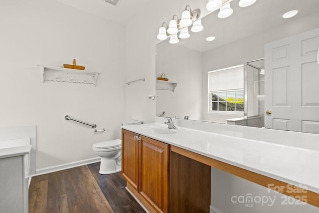 full bathroom featuring vanity, toilet, a shower with shower door, baseboards, and wood finished floors