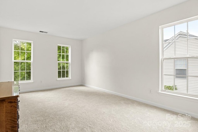 spare room featuring baseboards, visible vents, and carpet floors