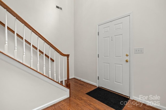 foyer with baseboards, visible vents, wood finished floors, and stairway