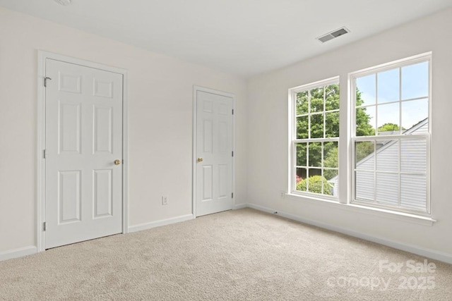 unfurnished bedroom featuring baseboards, visible vents, and light colored carpet