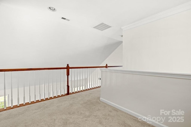 hallway with lofted ceiling, visible vents, baseboards, ornamental molding, and carpet