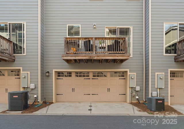rear view of house with a balcony, central AC unit, and an attached garage