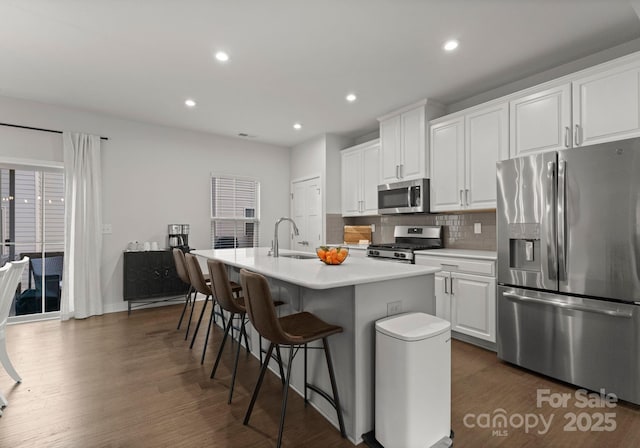 kitchen with dark wood-style flooring, a center island with sink, stainless steel appliances, and a sink