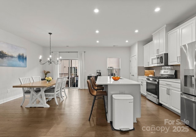 kitchen with a center island, a sink, white cabinetry, a chandelier, and appliances with stainless steel finishes