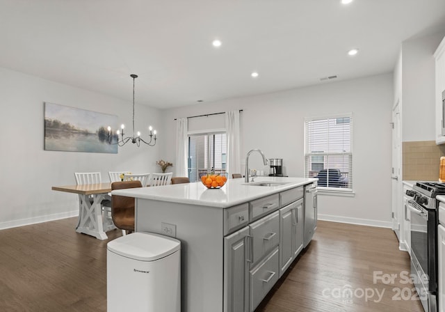 kitchen with a sink, gray cabinets, a wealth of natural light, dark wood-style floors, and range with gas stovetop