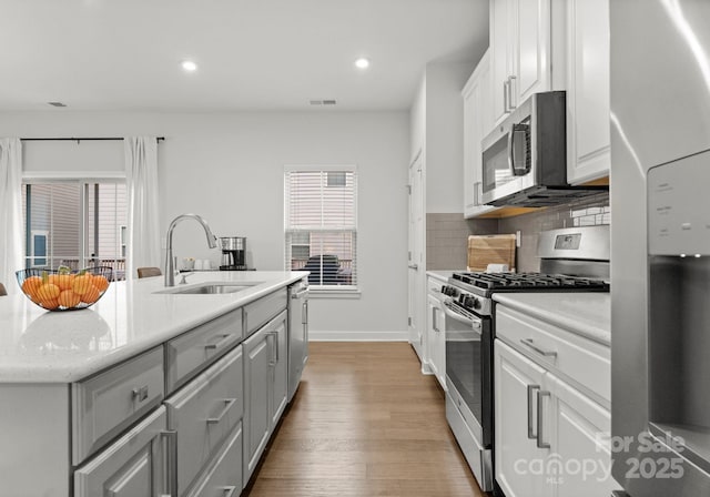 kitchen featuring a sink, stainless steel appliances, visible vents, light wood finished floors, and white cabinets