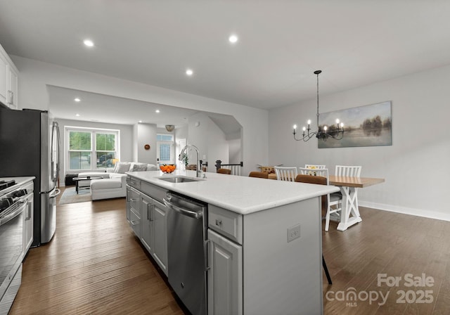 kitchen featuring a sink, stainless steel appliances, a center island with sink, open floor plan, and gray cabinetry