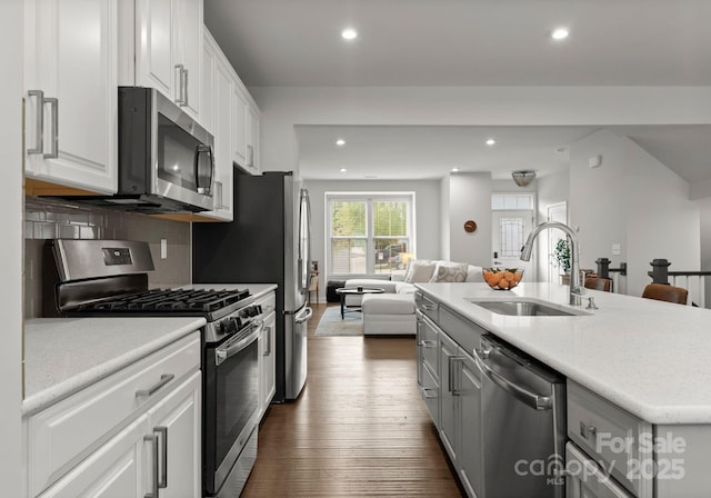 kitchen featuring stainless steel appliances, open floor plan, recessed lighting, and a sink