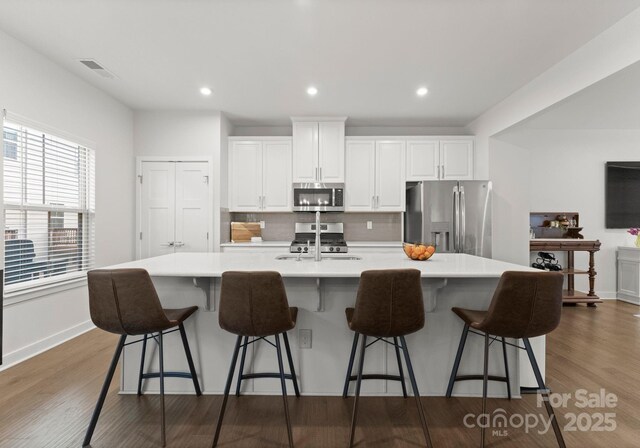 kitchen featuring a sink, stainless steel appliances, white cabinetry, and a large island