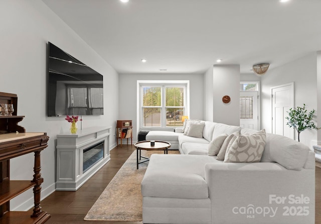 living room with baseboards, a glass covered fireplace, recessed lighting, and dark wood-style floors